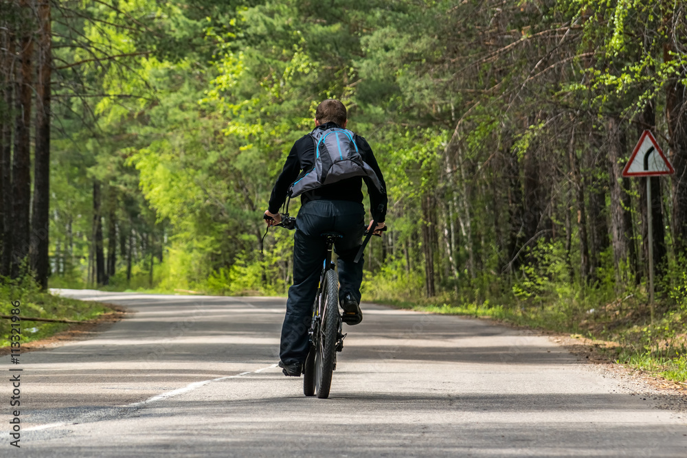 cyclist rides along the road in the forest cyclist rides along the road in the forest