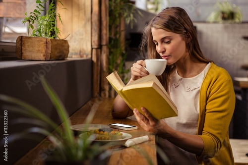 Casual woman reading a book while drinking photo