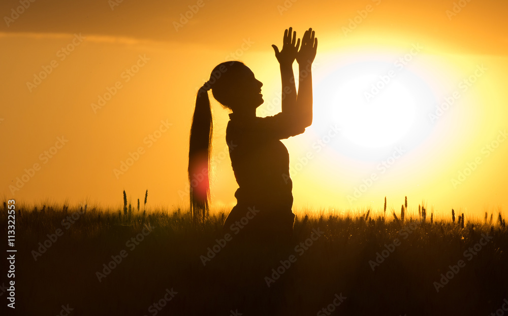 Silhouette of girl clapping hands at sunset