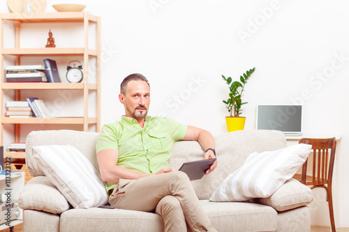 Picture of handsome man using tablet PC at home. Serious man using computer technologies for business purposes.