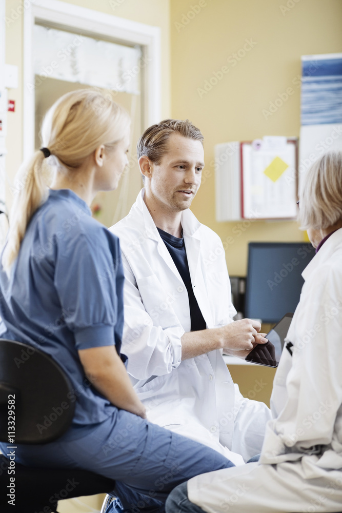 Doctors and nurse discussing over digital tablet in hospital Doctors and nurse discussing over digital tablet in hospital