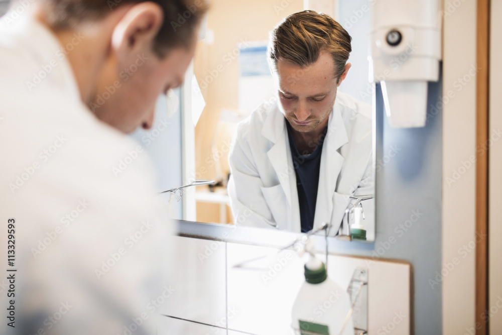 Mirror reflection of male doctor in hospital bathroom Mirror reflection of male doctor in hospital bathroom