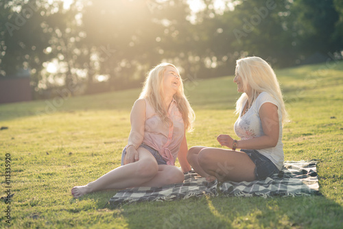 Zwei junge Frauen unterhalten sich auf Wiese am See / Schwimmbad photo