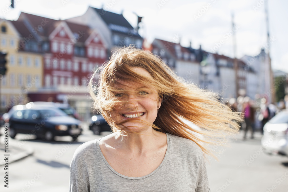 Portrait of happy woman with windswept hair on city street Portrait of happy woman with windswept hair on city street