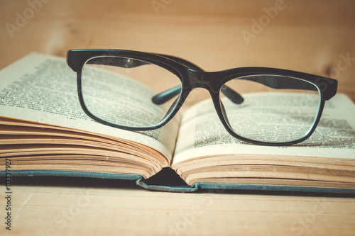 Old books and glasses on a wooden table with filter effect retro