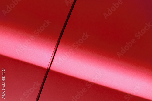 Surface of red sport sedan car, detail of metal fender and door of vehicle bodywork 