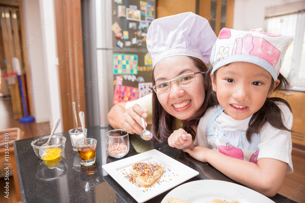 Asian mother and daughter enjoy making pancake in kitchen Asian mother and daughter enjoy making pancake in kitchen