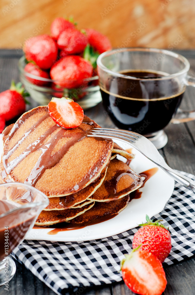 
easy hearty and healthy breakfast , American pancakes with strawberries and chocolate with coffee on a wooden background