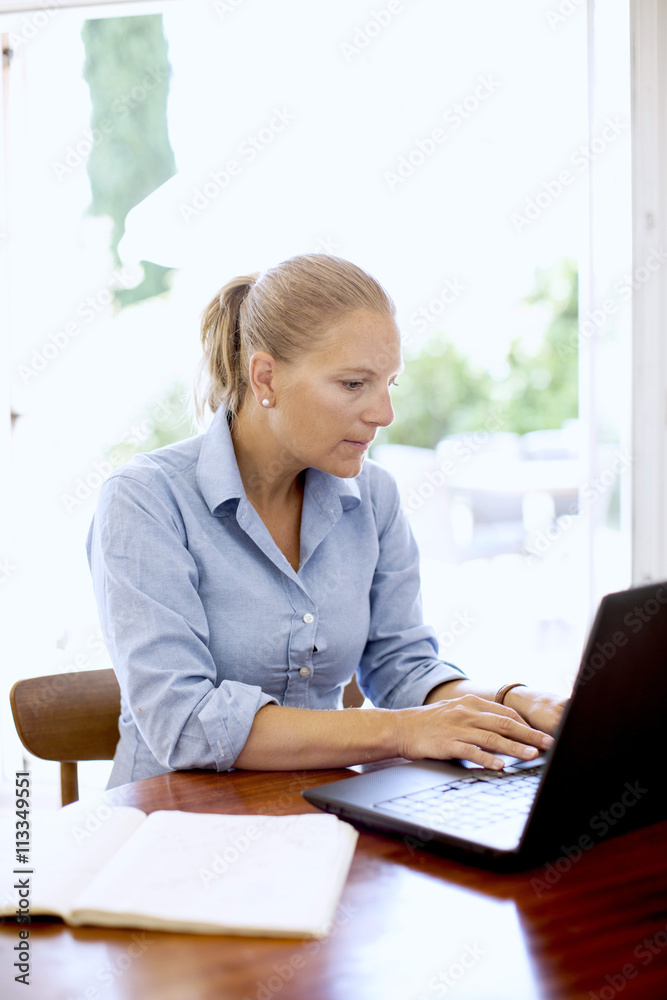 Mid adult woman using laptop at home Mid adult woman using laptop at home