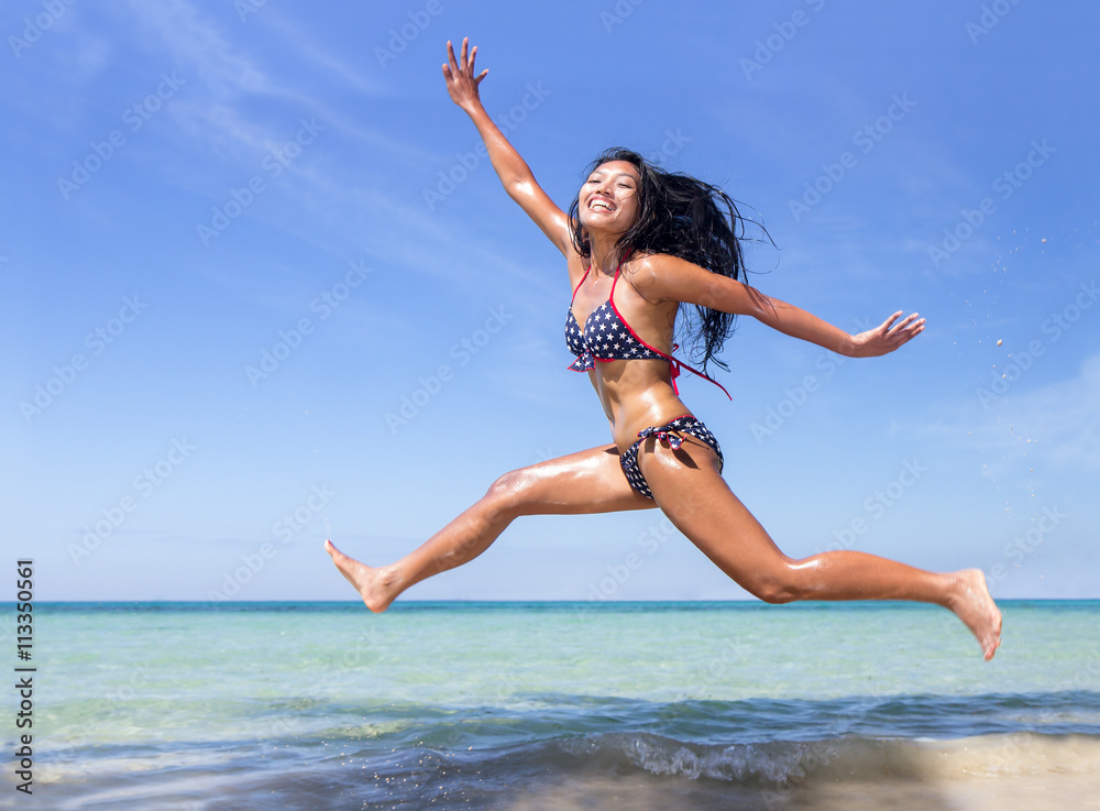 Attractive woman in bikini jumping on the sea beach
