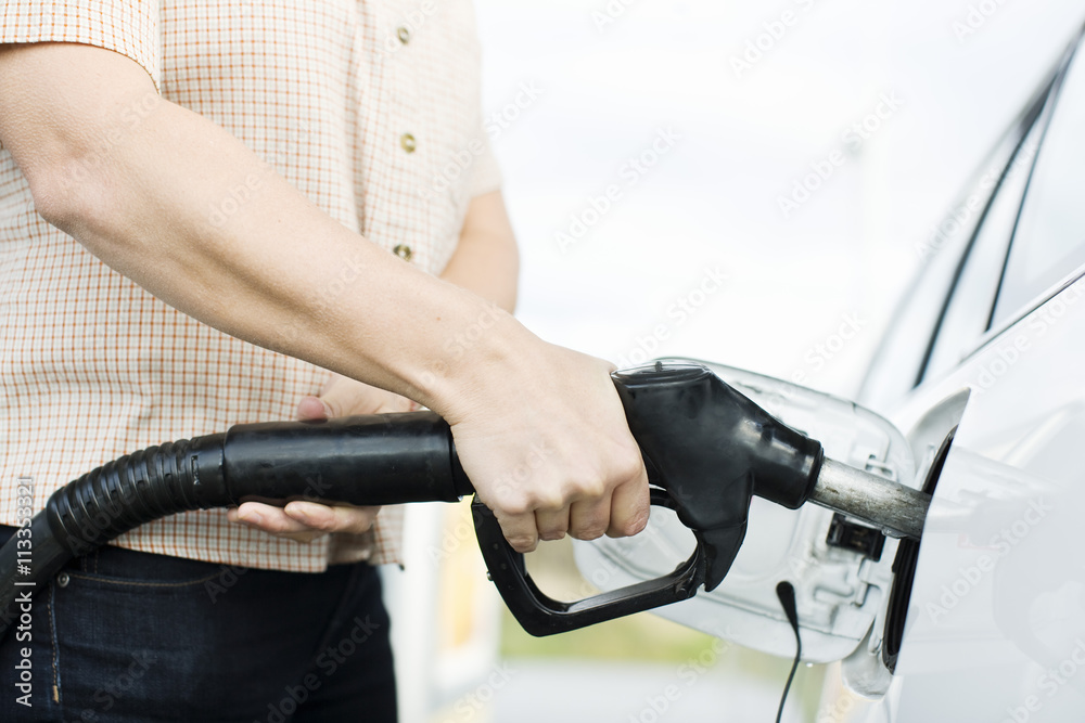 Midsection of woman fueling car with pump in gas station Midsection of woman fueling car with pump in gas station