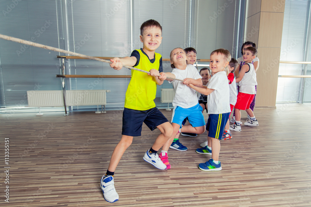 Obraz premium Group of kids pulling a rope in fitness room