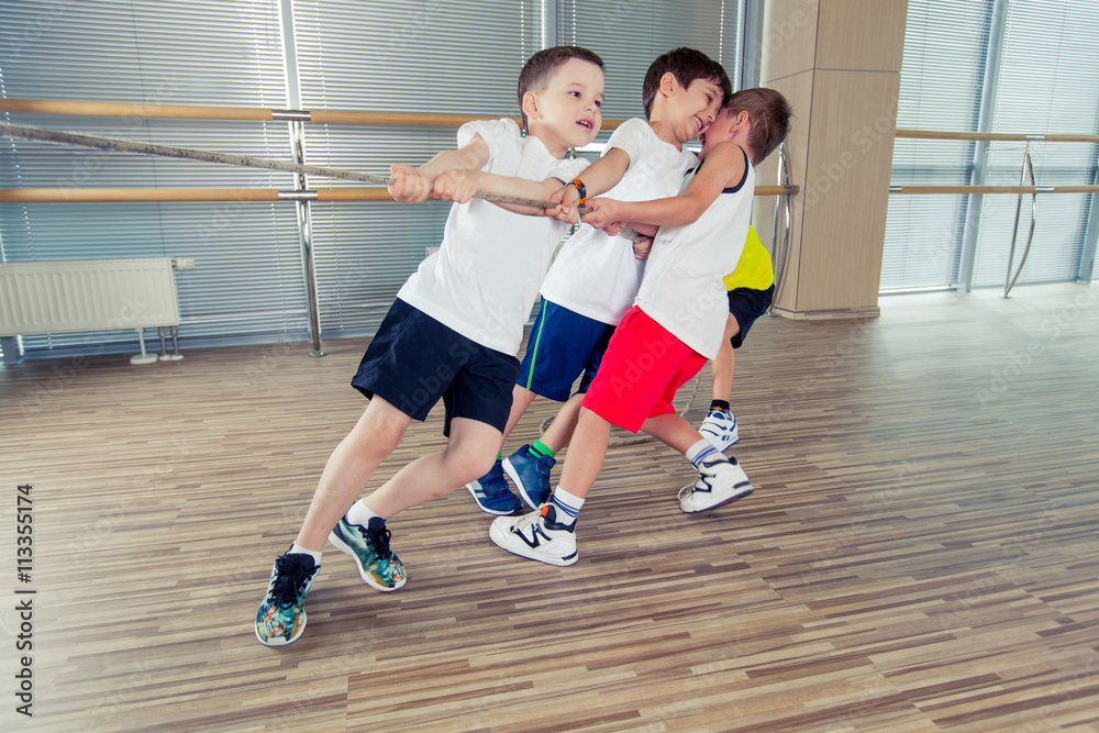Group of kids pulling a rope in fitness room