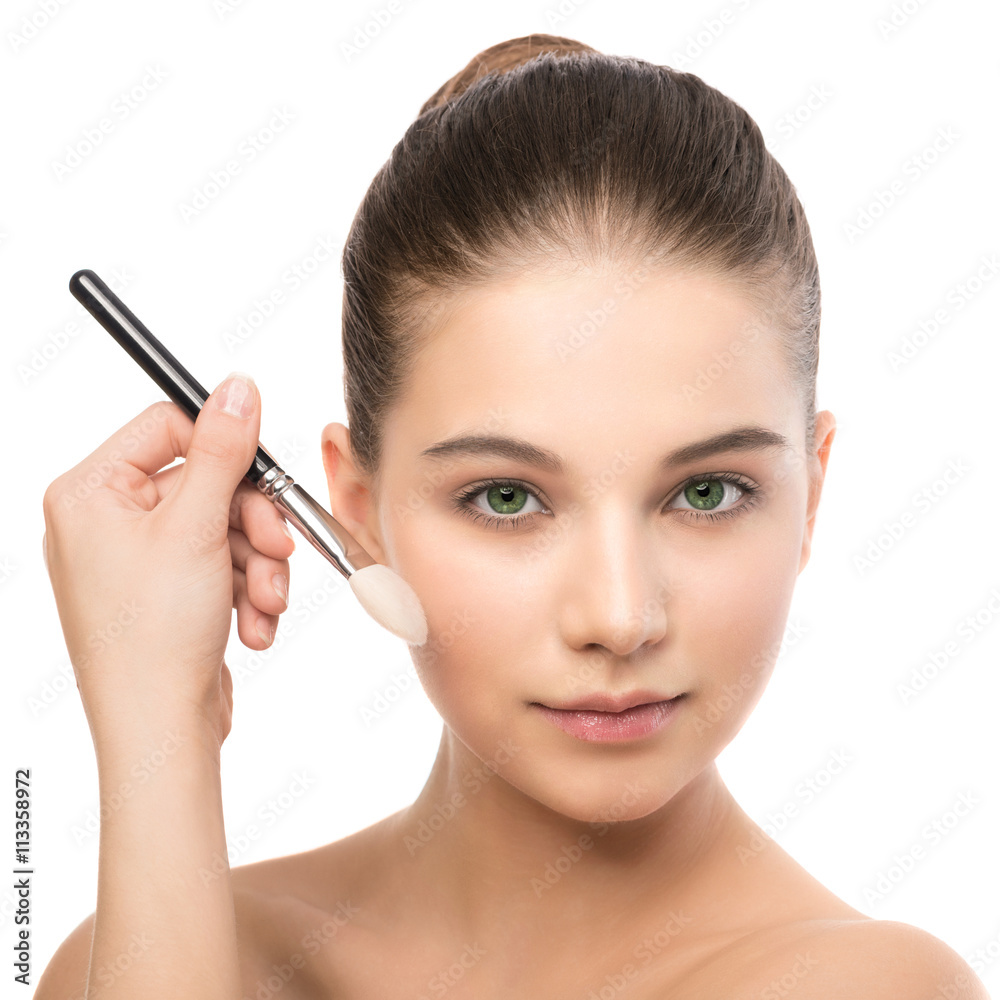 Portrait of beautiful young brunette woman with clean face. Beauty spa model girl with perfect fresh clean skin applying cosmetic brush. Youth and skin care concept. Isolated on a white background.