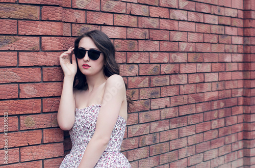 girl with red lips in the sunglasses and in the sundress near th
