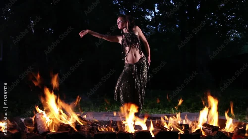 Pretty young woman dancing in the night with a fire flame in the foreground
Pretty young woman dancing in the night with a fire flame in the foreground
