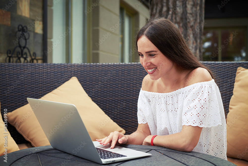 Young beautiful woman sitting in the yard and scrolling in lapto Young beautiful woman sitting in the yard and scrolling in lapto
