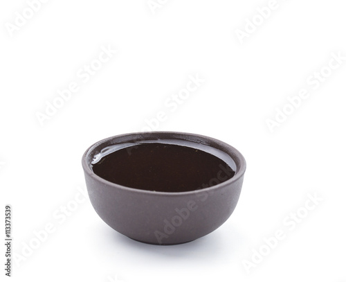 Soy sauce in brown bowl isolated on white background. Closeup.