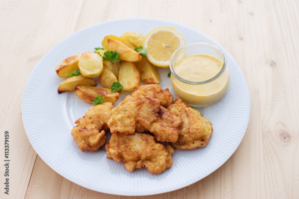 Cod fish in batter or cod fritters served with baked potatoes with parsley leaves and home made mayonnaise sauce and half of lemon served on the simple white plate. Light dish for lunch or diner. Cod fish in batter or cod fritters served with baked potatoes with parsley leaves and home made mayonnaise sauce and half of lemon served on the simple white plate. Light dish for lunch or diner.