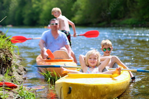 Family kayaking on the river. Active father with children, two teenage boys and little girl, having fun together enjoying adventurous experience with kayak on a sunny day during summer vacation