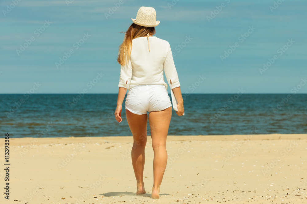 Back view of long haired woman on beach.
