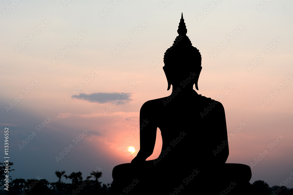 Silhouette of Buddha with sun shining from behind.