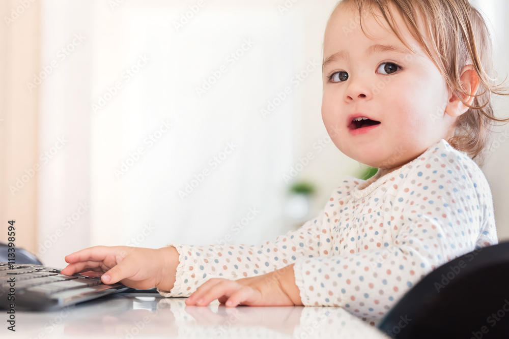 Little toddler girl typing on her computer keyboard looking Little toddler girl typing on her computer keyboard looking