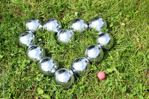 Bild auf Leinwand Petanque balls in the shape of a heart on the grass