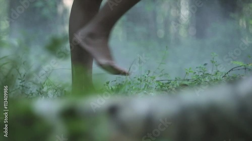 Close up of girl bare feet walking on a green grass in the forest