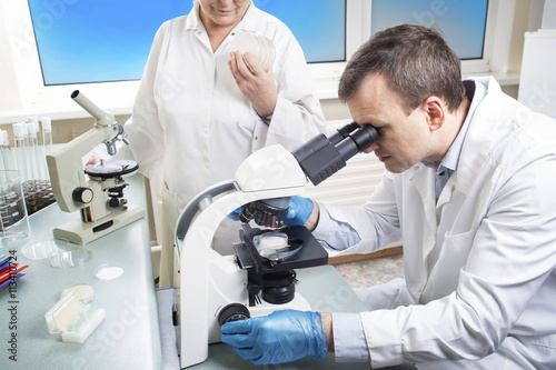 Portrait of caucasian male chemist scientific researcher using microscope in the laboratory interior