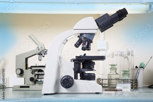 Photo of a professional ocular laboratory microscope with stereo eyepiece in laboratory interior.