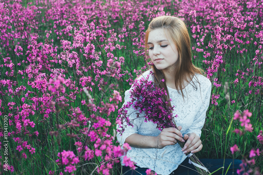beautiful bride in a flower field. The girl in a white dress with a bouquet in a summer field at sunset beautiful bride in a flower field. The girl in a white dress with a bouquet in a summer field at sunset