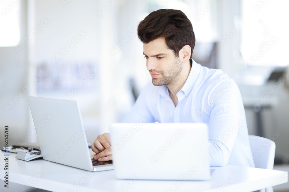 Solve the problem. Young businessman working on the solution of the problems on laptop at office Solve the problem. Young businessman working on the solution of the problems on laptop at office