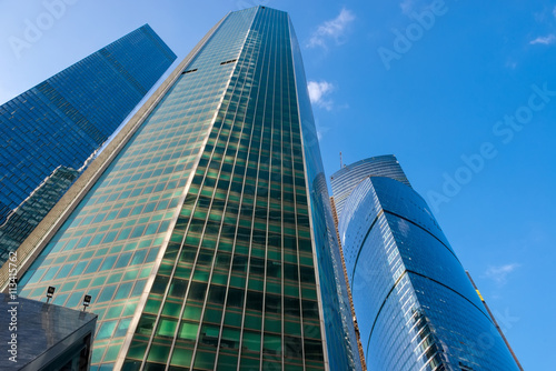 Steel and glass corporate buildings reflect the sky and clouds,