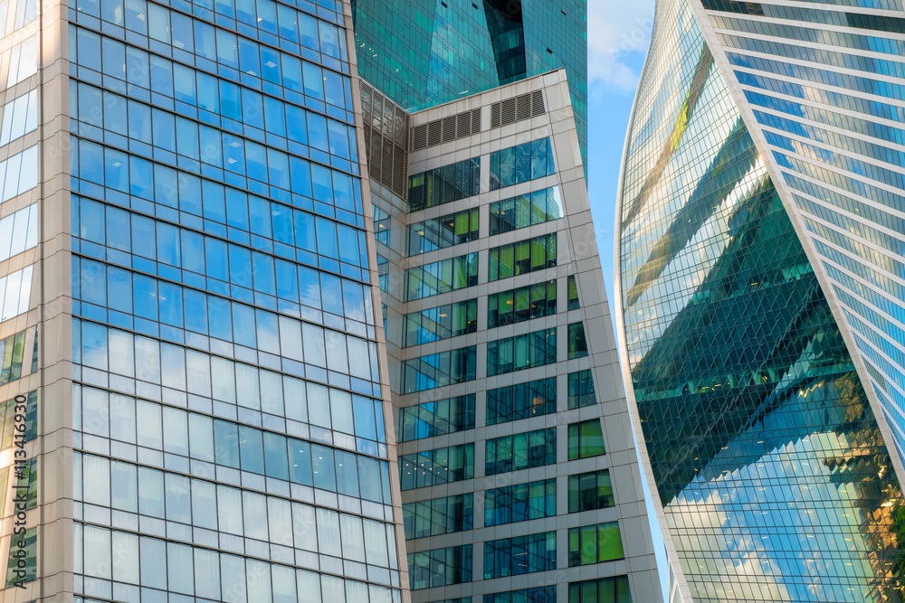 Fototapeta premium Steel and glass corporate buildings reflect the sky and clouds,