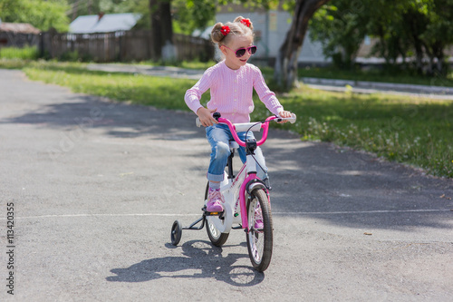 girl in sunglasses riding on a bicycle summer sunny day