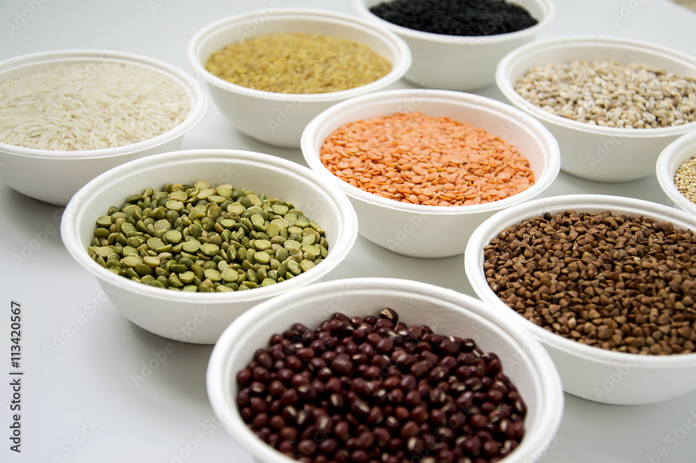 Different kinds of groats in small white bowls on white background Different kinds of groats in small white bowls on white background