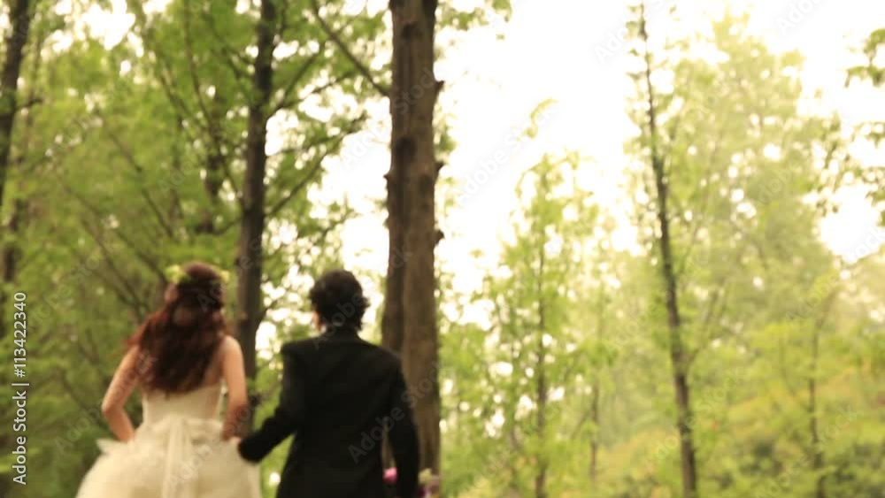 Bride and groom holding hands together and running at green forest park Bride and groom holding hands together and running at green forest park