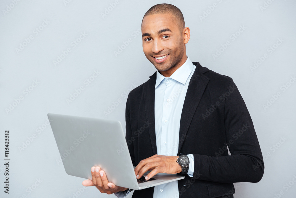 Happy african american young man holding and using laptop Happy african american young man holding and using laptop