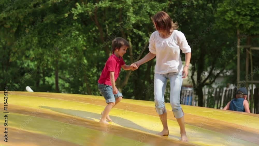 Mother and child jumping on a big trampoline, summertime Mother and child jumping on a big trampoline, summertime