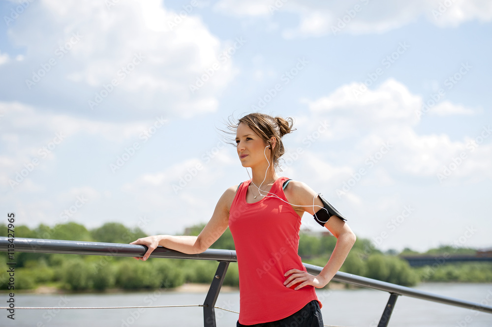 Fit woman jogger resting after run listening music.