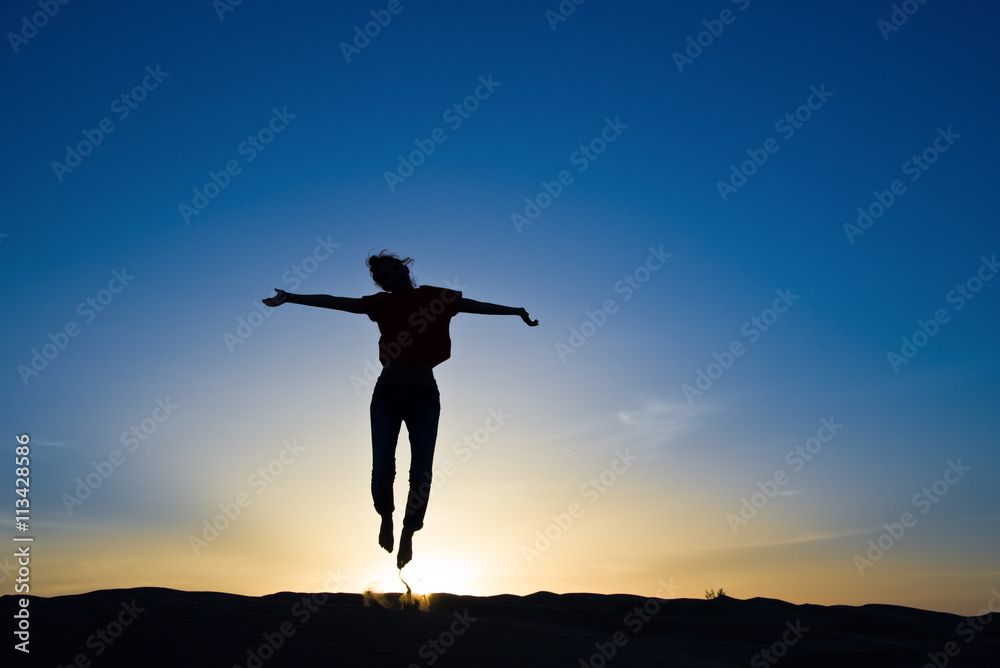 Silhouette of a woman jumping in the sunlight