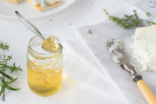 Herb and white wine  jelly in jar to serve on crackers with blue gorgonzola cheese. Selective focus photo