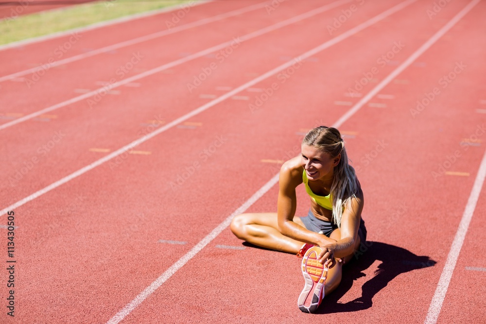Fototapeta premium Female athlete warming up on the running track