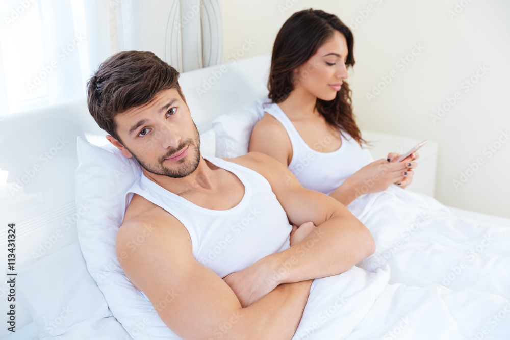 Husband while his internet addict wife is using mobile phone Husband while his internet addict wife is using mobile phone