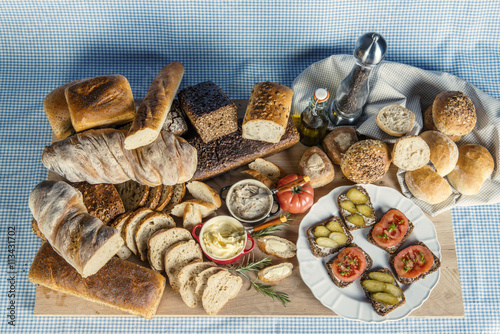 Stół zastawiony chlebem, warzywami, smalcem i przyprawami na śniadanie w kompozycji na tle obrusu