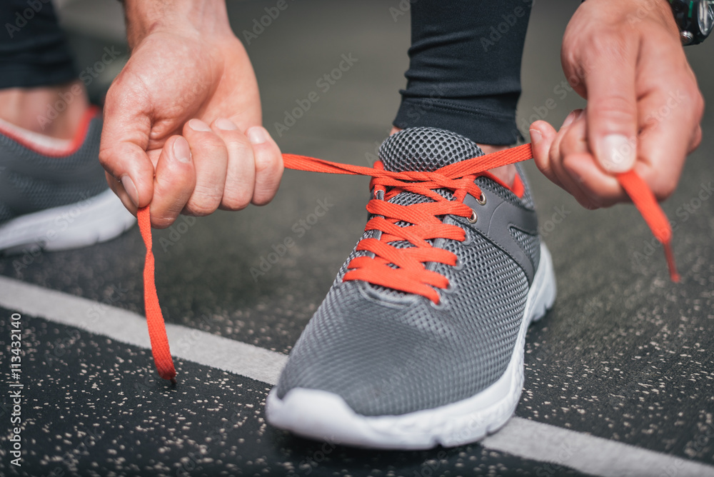 Running footwear close up. Gym indoor workout and fitness healthy concept.  Male athlete tying sport shoes laces before training. Stock Photo | Adobe  Stock