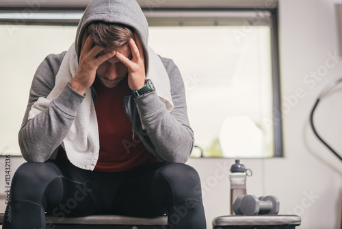 Tableau sur toile Strong sporty man sitting on gym bench suffering depression to overcome