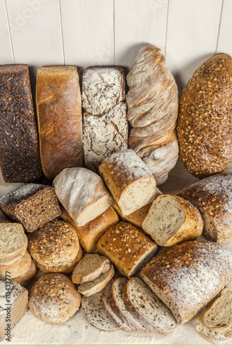 Stos różnych chlebów, jasnych i ciemnych, pełnoziarnistych, obsypanych mąką - aranżacja