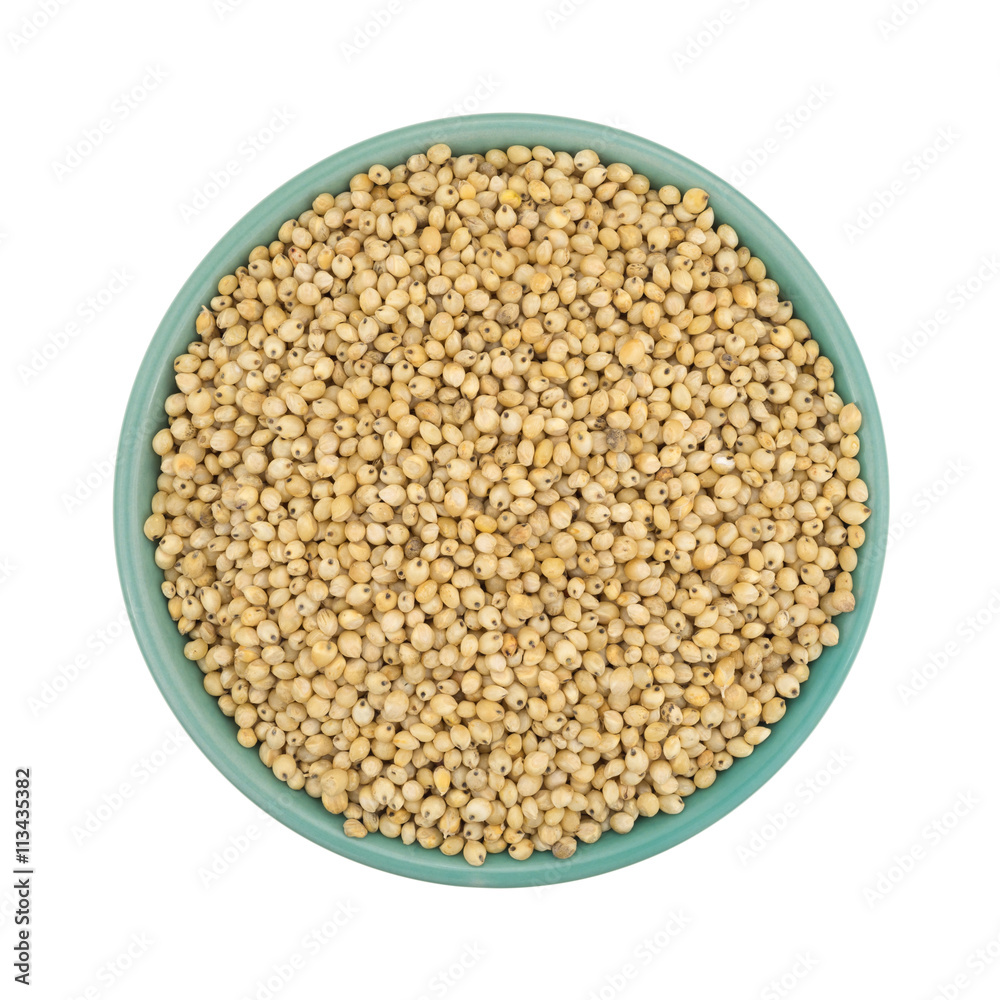 Whole grain sorghum seeds in a bowl isolated on white background top view.